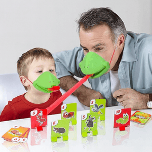 Father and son playing Frog Mouth Tongue-Out table game with green frog masks and red stretchy tongues at home.